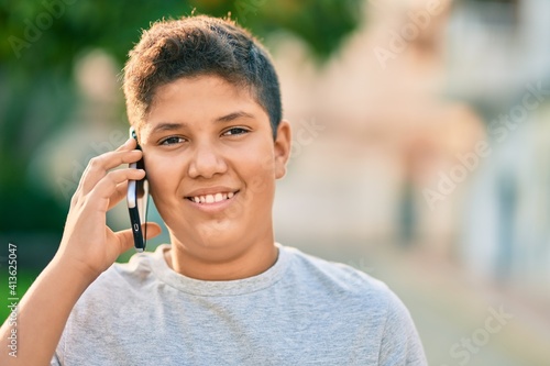 Adorable latin boy smiling happy talking on the smartphone at the city.