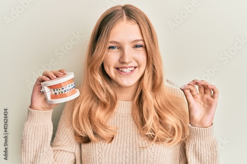 Beautiful young caucasian girl holding invisible aligner orthodontic and braces smiling with a happy and cool smile on face. showing teeth. photo