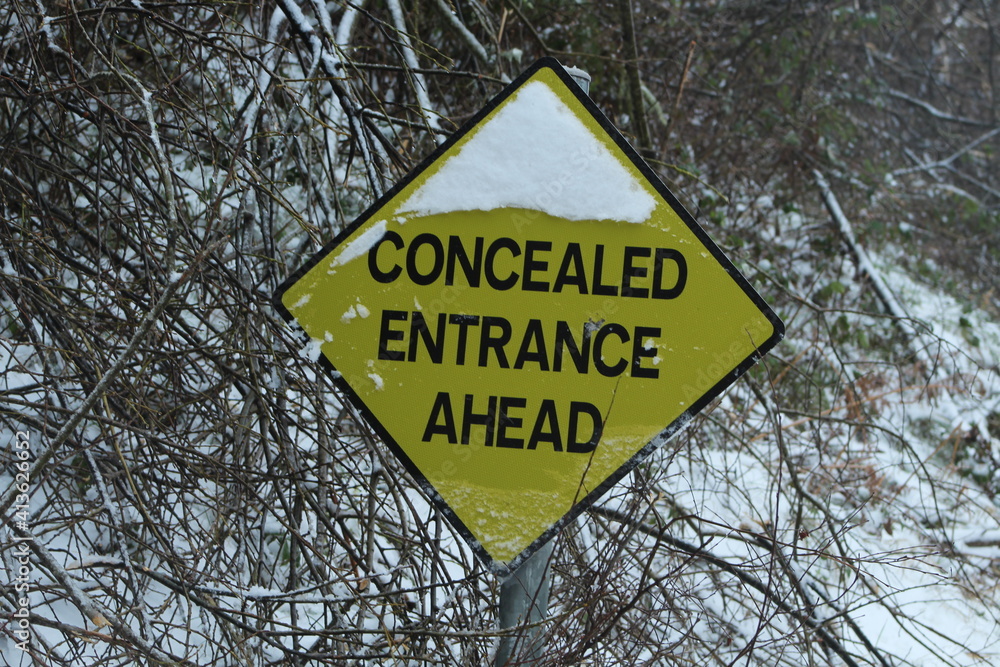 Concealed Entrance ahead sign - Yellow and black Irish Road Sign with snow on sign