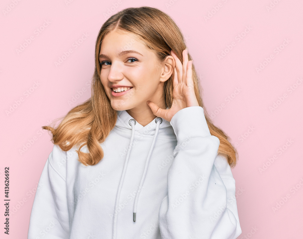 Beautiful young caucasian girl wearing casual sweatshirt smiling with hand over ear listening an hearing to rumor or gossip. deafness concept. Beautiful young caucasian girl wearing casual sweatshirt smiling with hand over ear listening an hearing to rumor or gossip. deafness concept.