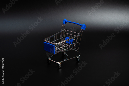 Small blue shopping cart on a black background. Copspace