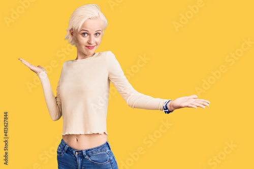 Young blonde woman wearing casual clothes clueless and confused expression with arms and hands raised. doubt concept.