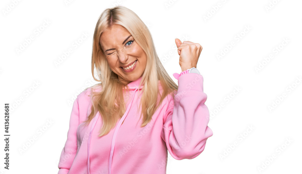 Young blonde woman wearing casual sweatshirt angry and mad raising fist frustrated and furious while shouting with anger. rage and aggressive concept. Young blonde woman wearing casual sweatshirt angry and mad raising fist frustrated and furious while shouting with anger. rage and aggressive concept.