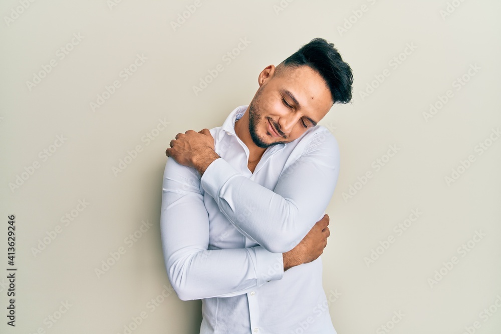Young arab man wearing casual clothes hugging oneself happy and positive, smiling confident. self love and self care Young arab man wearing casual clothes hugging oneself happy and positive, smiling confident. self love and self care