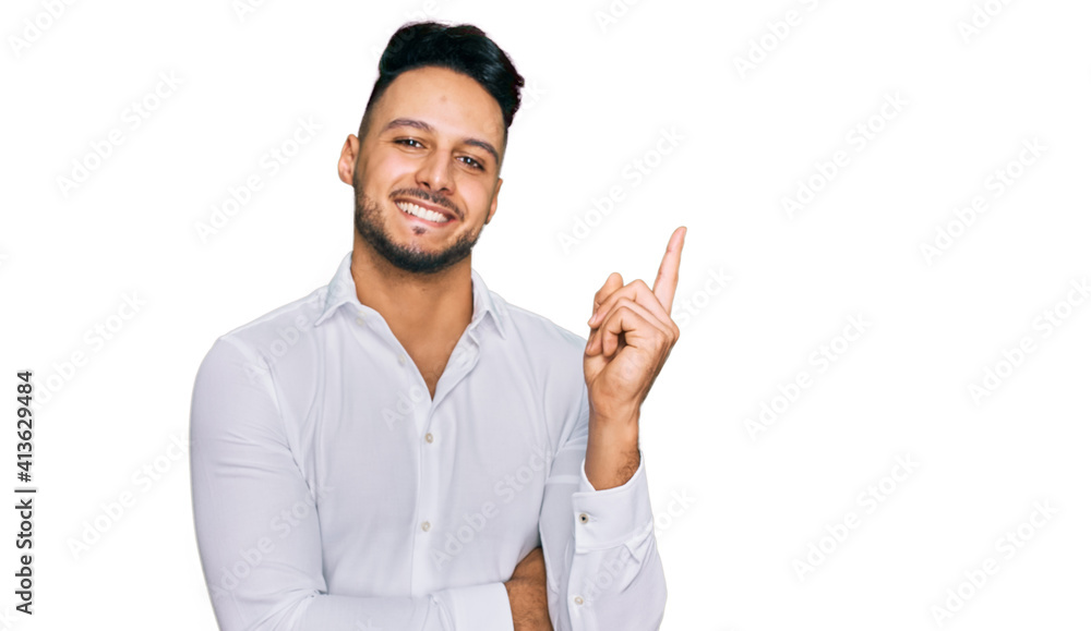 Young arab man wearing casual clothes with a big smile on face, pointing with hand and finger to the side looking at the camera. Young arab man wearing casual clothes with a big smile on face, pointing with hand and finger to the side looking at the camera.