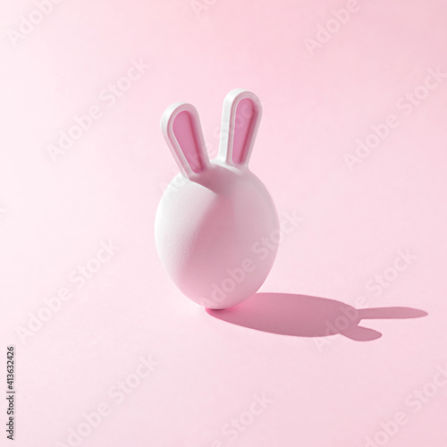 Easter egg with bunny ears on a pink background. A creative Easter concept.