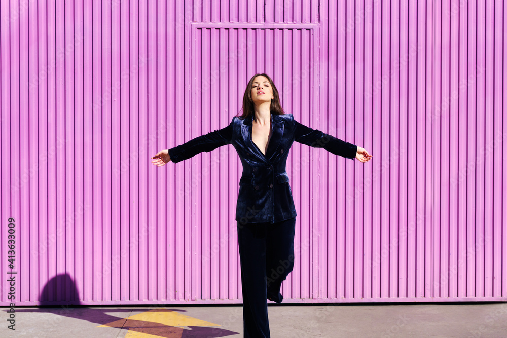Woman wearing blue suit posing near pink shutter with open arms. Woman wearing blue suit posing near pink shutter with open arms.