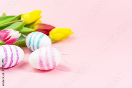 Easter painted eggs with tulips on a pink background. Copy space. Easter celebration concept.