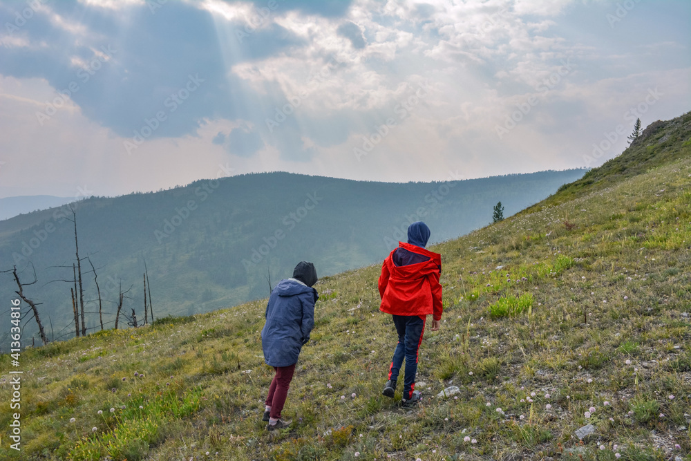 tourists climb the mountainside and look at the stormy sky