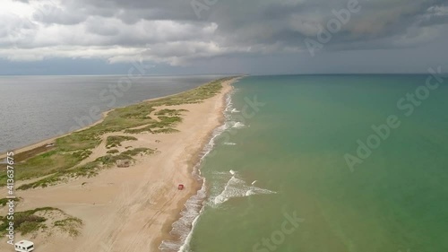 Flight along the beach at the Bugaz spit at The Black Sea. A red car moving along the beach. photo