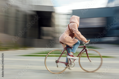 Young woman in face medical mask riding bicycle roadway motion blur