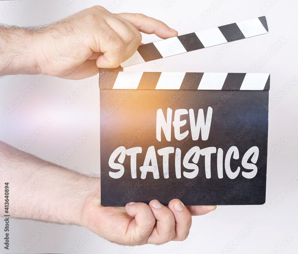 Obraz premium On a white background, a man holds a clapperboard in his hands on which it is written - NEW STATISTICS