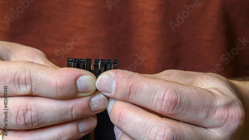 Closeup man hands hold PCI Express power supply connector for graphics card. Male fingers with nails without manicure
