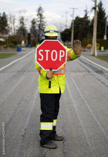 Masked flagger at work holding stop sign