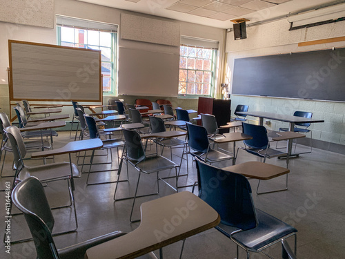 A Shadowy, Empty Classroom in a School with Chairs Facing a Chalkboard on a Sunny Day