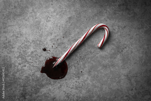 Moody Top-Down Shot of a Red and White Candy Cane, with a Sharpened Point lying in a Pool of Dark Red Blood-like Liquid