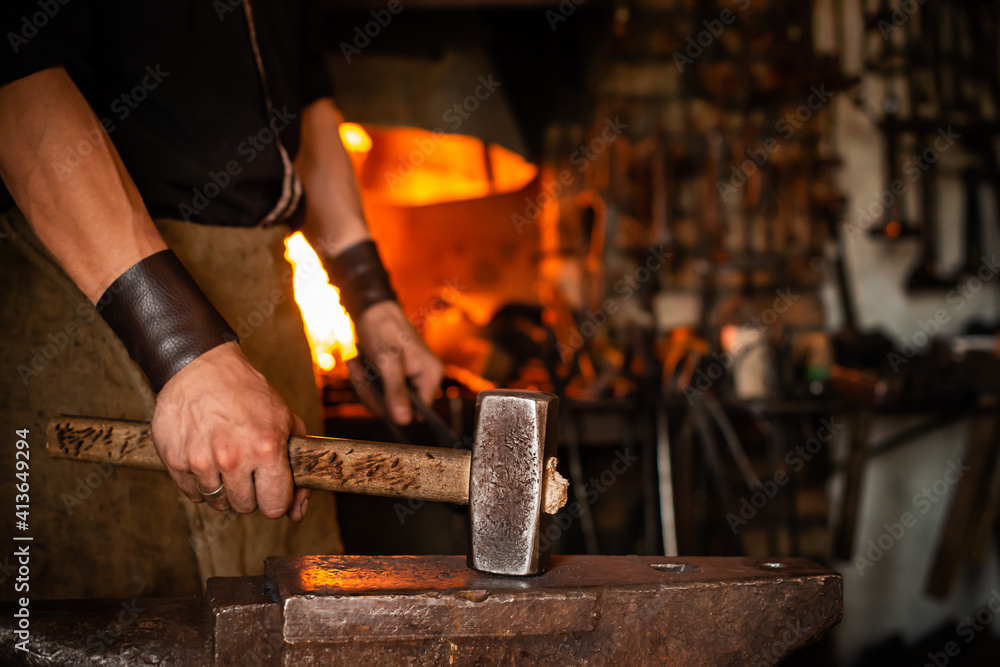 blacksmith performs the forging of hot glowing metal on the anvil blacksmith performs the forging of hot glowing metal on the anvil