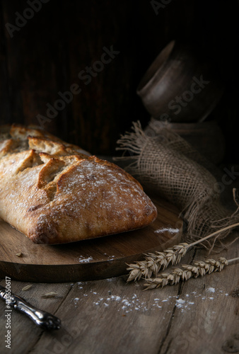 Fresh bread and ears of wheat on a rustic table