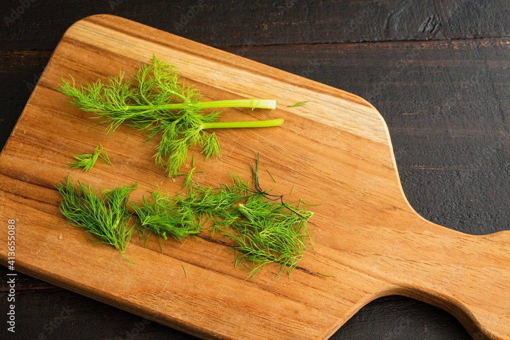 Fennel Fronds on a Cutting Board: Sprigs of raw fennel leaves on a wooden cutting board Fennel Fronds on a Cutting Board: Sprigs of raw fennel leaves on a wooden cutting board