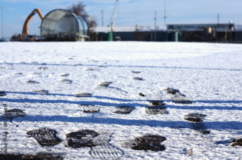Close up of footprints in a snowy car park with soft-focus background