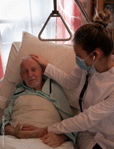 Nurse taking care of old man in bed in hospital photo