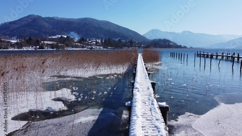 Aerial shot of a snowy jetty in the lake Tegernsee in Bavaria, Germany. Snowy dock in a mountain lake in the alps.