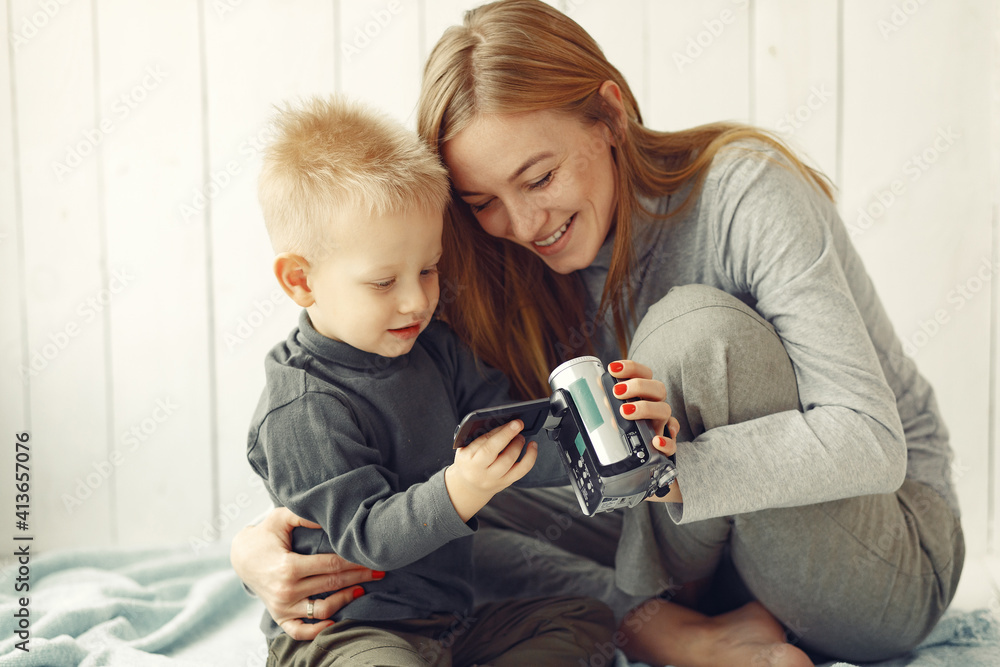 Beautiful woman with child. Woman in a gray sweater. Family use the camera. Beautiful woman with child. Woman in a gray sweater. Family use the camera.