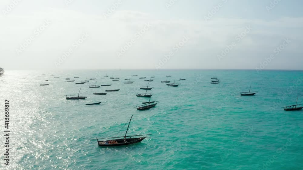 Aerial shot of the fisherman boat floating on turquoise Indian ocean waves near the Zanzibar island, Tanzania. Drone point top view 4K footage. Traveling and fishing industry concept video. Aerial shot of the fisherman boat floating on turquoise Indian ocean waves near the Zanzibar island, Tanzania. Drone point top view 4K footage. Traveling and fishing industry concept video.