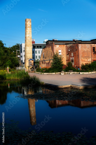 Photography A tall tower at the old Evergreen (formerly Don Valley) Brickworks in Toronto, Ontario reflects in a pond in the late afternoon sun