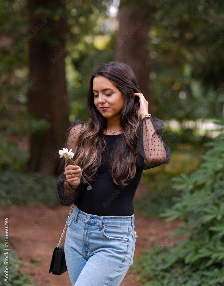 Beautiful young woman in forest holding flower Beautiful young woman in forest holding flower