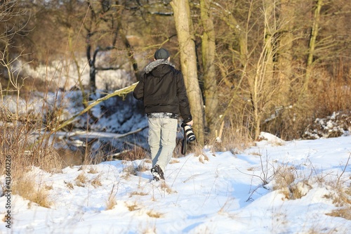 man with a photo camera is walking in winter scenery