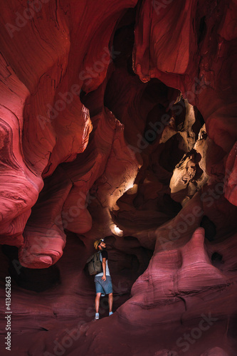 Tourist man adventurer standing in Coves De Can Riera caves in Torrelles, Barcelona, Catalonia, Spain. Amazing sandstone formation inside a cave. Concept of travel, explore and discover hidden places. photo