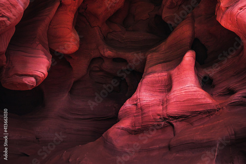 Amazing sandstone formations inside a cave in Coves De Can Riera caves in Torrelles, Barcelona, Catalonia, Spain. Vibrant red colors of eroded rock with wave forms similar to famous Grand Canyon, USA. photo