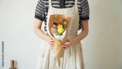 Mujer sosteniendo un arreglo floral envuelto de papel