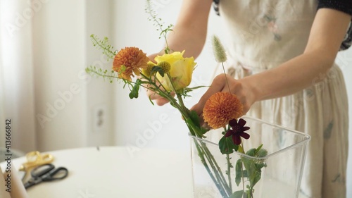 Mujer acomodando el arreglo floral de orquídea, rosas