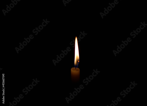 A white candle light burning in the dark in the middle of the frame.