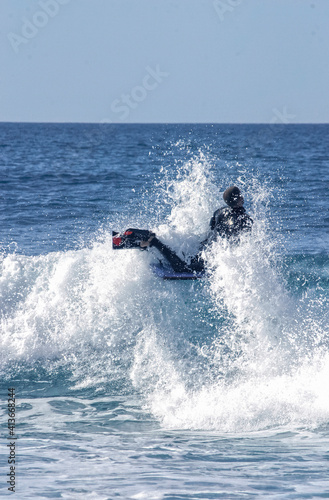 A water sportsman on his body-board turning on the top of a wave on a beach in France