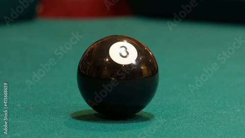 Black Eight Ball Shows Reflecton of a Man Adressing and Shooting it into the Corner Pocket of a Brunswick Pool Table after Practice Strokes using Cue Ball, Closeup with Green Felt or Cloth photo