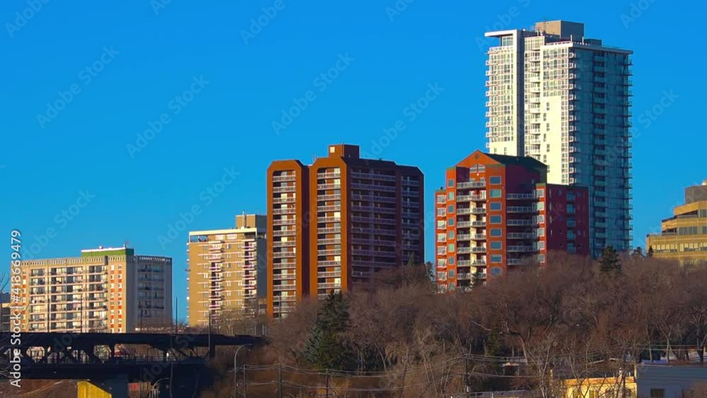 4k Stunning Blue clear sunny afternoon sklyline closeup of post modern apartment buildings towering over older condominiums by river valley of downtown Edmonton next to historic high level bridge