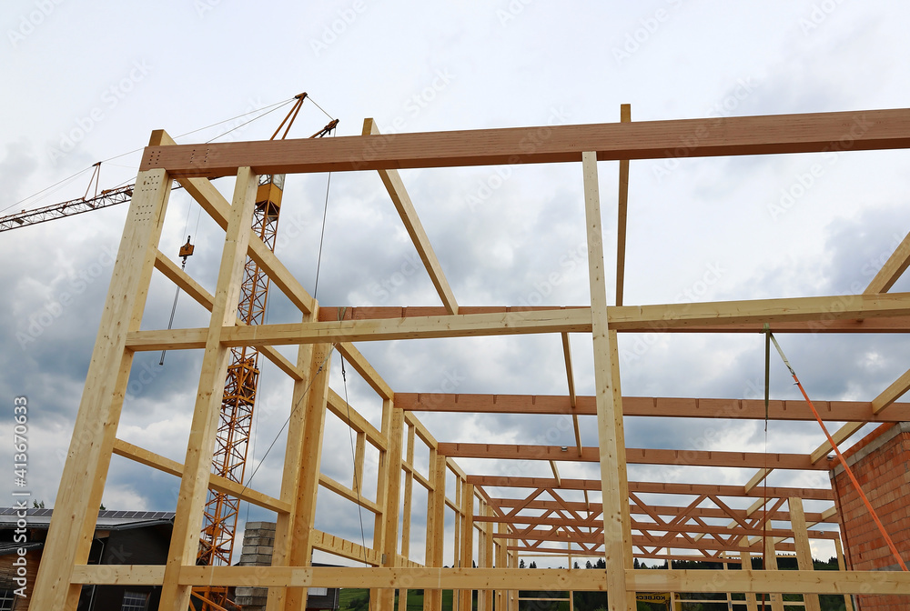 Holzbalken und Kran an einer Baustelle. Der Bau von einem großen Holzhaus. Holzbalken und Kran an einer Baustelle. Der Bau von einem großen Holzhaus.