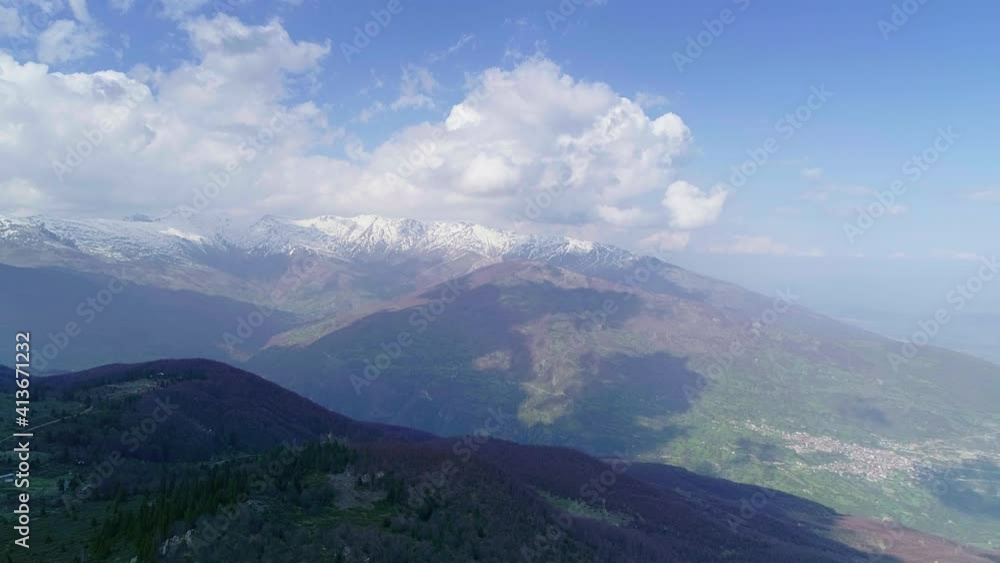 Beautiful mountain landscape with hilly horizon, snow peaks and cloudy sky, aerial forward motion view Beautiful mountain landscape with hilly horizon, snow peaks and cloudy sky, aerial forward motion view