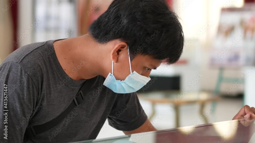 An Indonesia young man looking into glass display case An Indonesia young man looking into glass display case