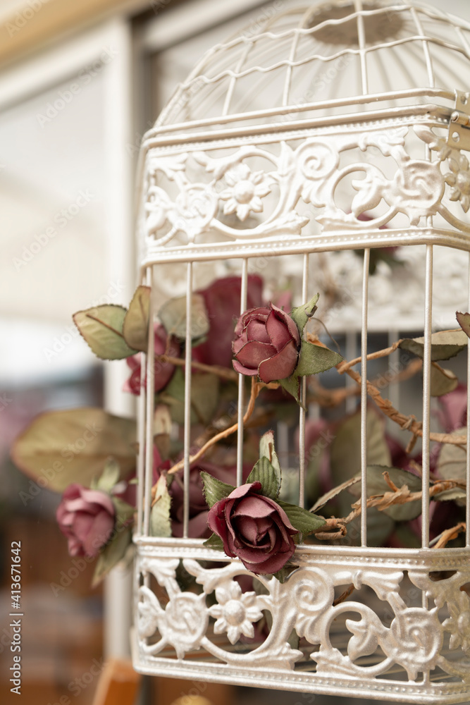 closeup to beautiful decoration of a white cage with dried red roses, vintage style