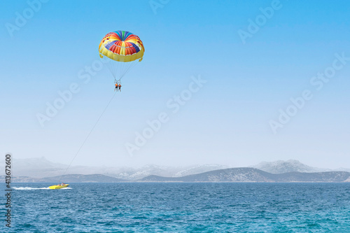 Couple of tourists flying on a colorful parachute on blue sky background. Copy space, holiday fun activities. Sea summer recreation - Turkey.