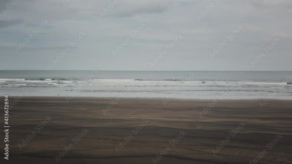 Open ocean with blue water and wave crashing onto deserted black sand beach in New Zealand Open ocean with blue water and wave crashing onto deserted black sand beach in New Zealand