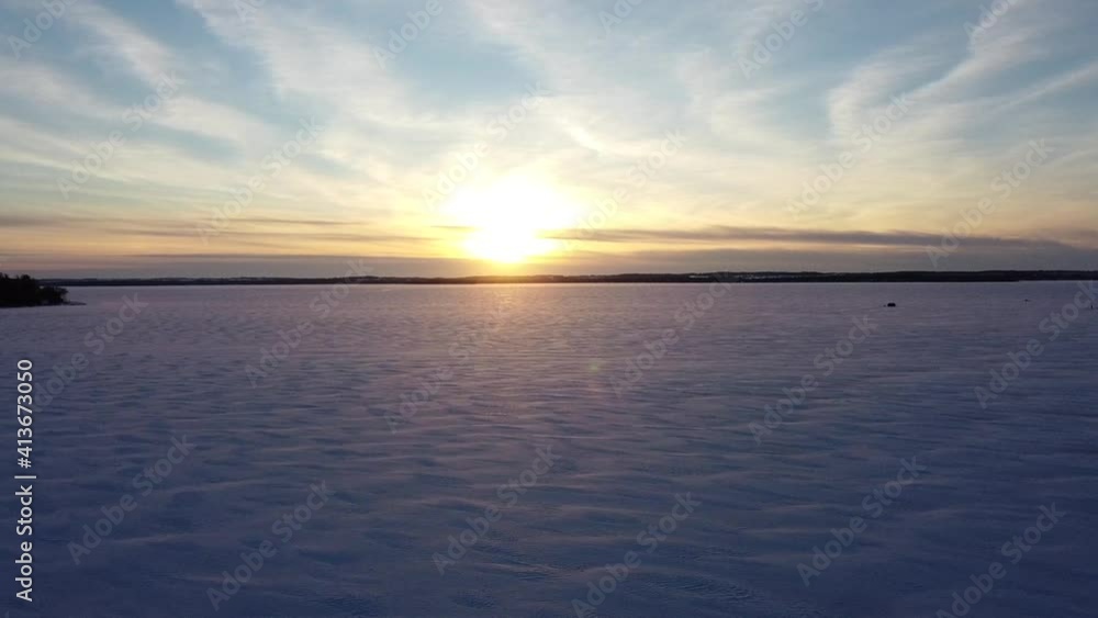 Sunset over vast snow covered frozen lake with ice fishing huts during winter; aerial Sunset over vast snow covered frozen lake with ice fishing huts during winter; aerial