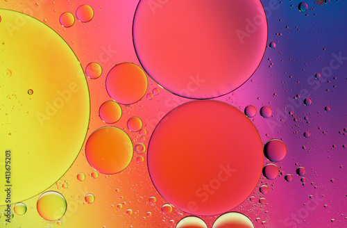 Olive oil drops suspended in water with colorful backgrounds photo