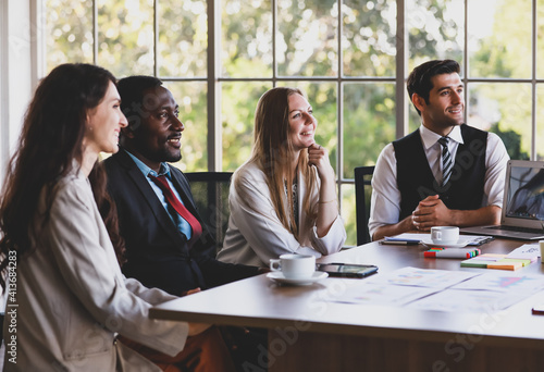 Group of four professional multiethnic businessmen and businesswomen sitting and concentrated listening to an idea of a new project in a multiracial organization meeting at the office working table