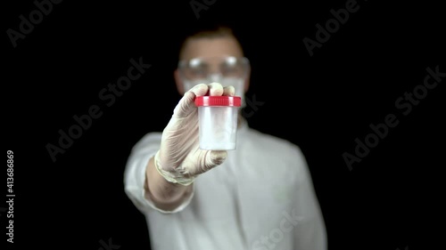 Sperm in a test bank close-up. Woman doctor holds out a jar of sperm to the camera on a black background. photo