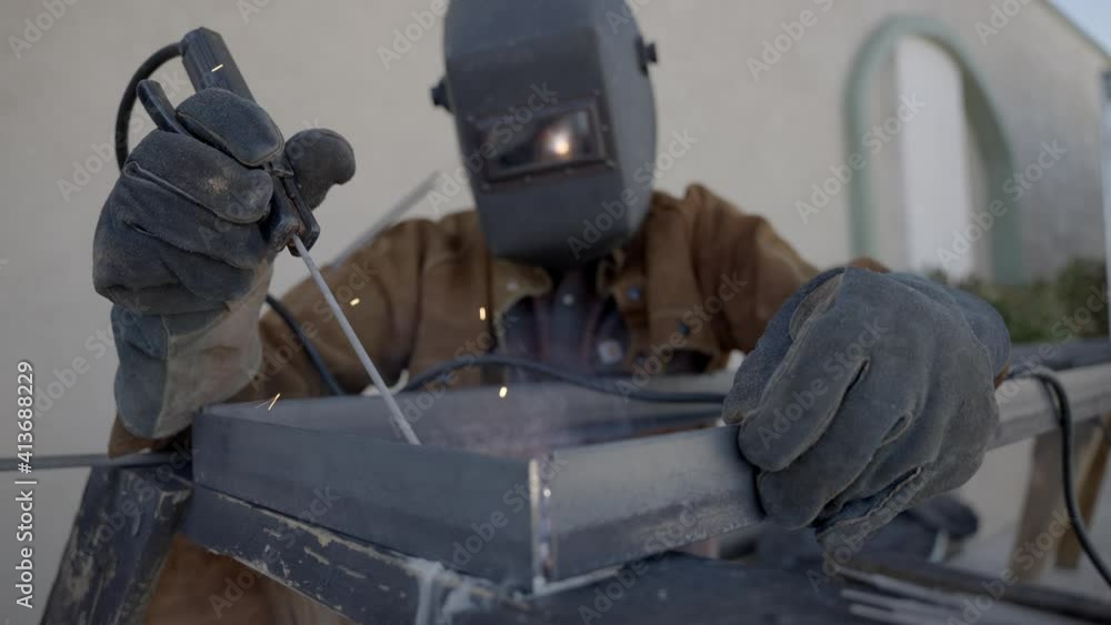 Front shot of welder working on welding a metal object, protective equipment Front shot of welder working on welding a metal object, protective equipment